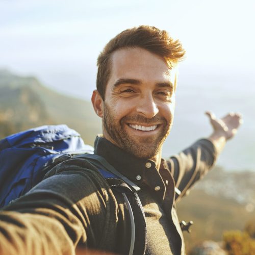 Shot of a young man taking selfies while hiking up a mountain